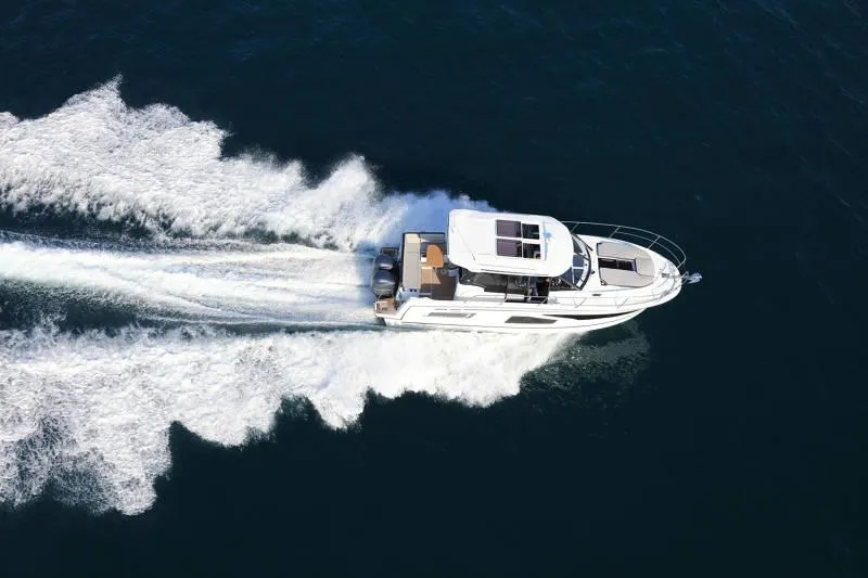 Slide: The Image of 2025 Jeanneau NC 1095 Weekender cruising on open water, aerial view. - 3