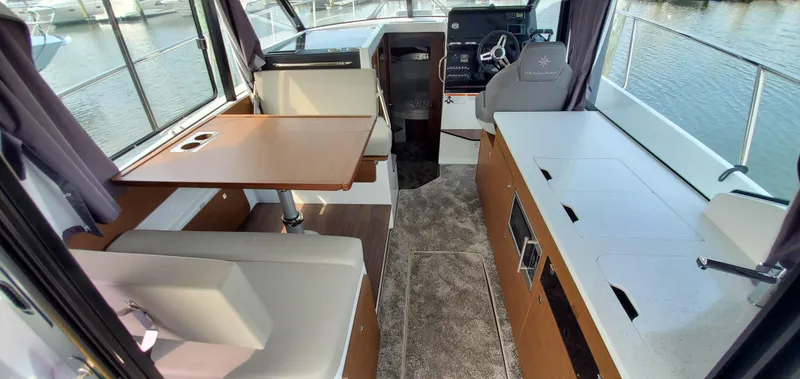Slide: The Image of 2025 Jeanneau NC 1095 Weekender interior with dining area, helm, and panoramic windows. - 6