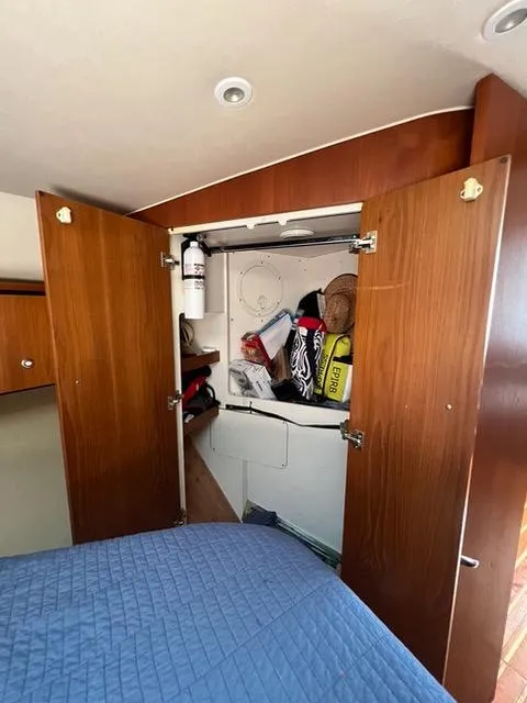 Slide: The Image of 2007 Tiara Yachts 4300 Sovran cabin storage with open wooden doors and various items inside. - 31