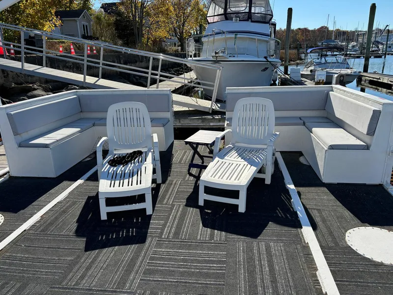 Slide: The Image of Custom 2022 MKI Pontoon Boat with seating and loungers at a marina. - 3