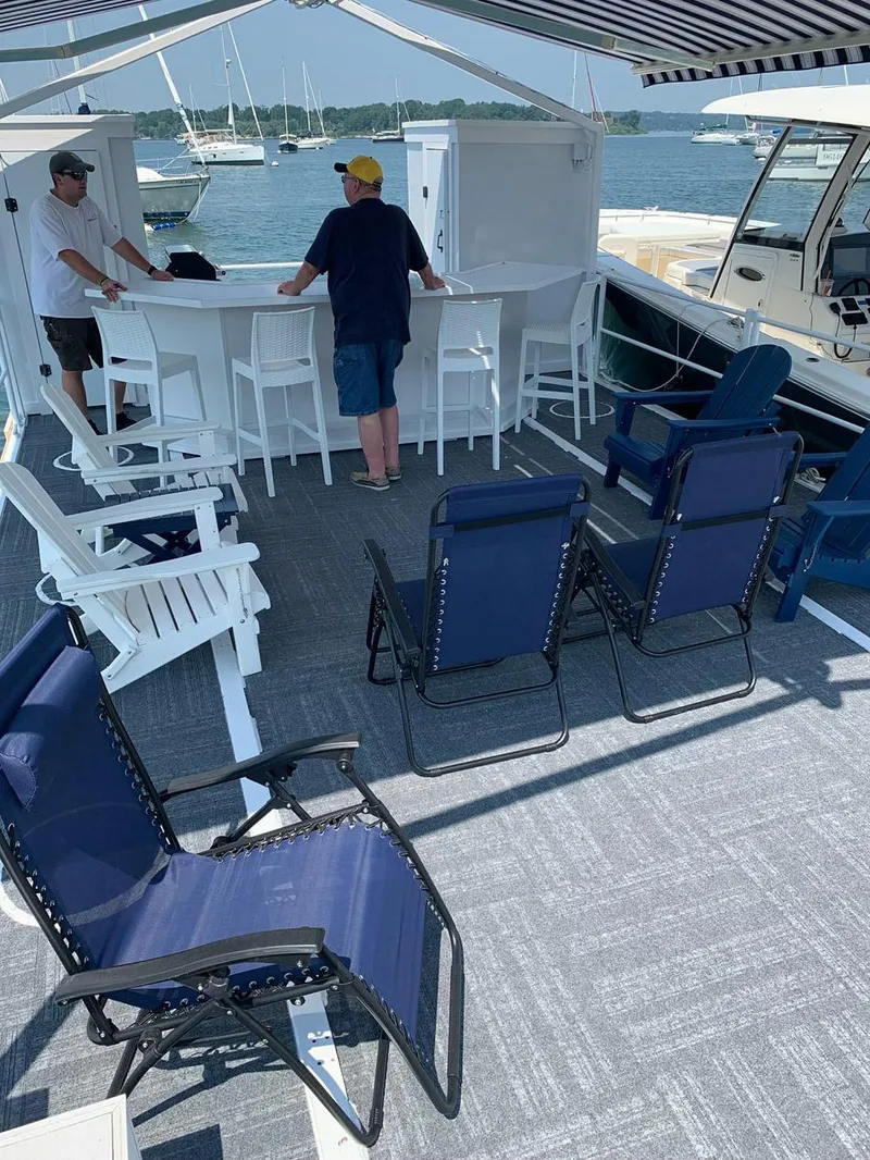 Slide: The Image of Custom 2022 MKI Pontoon Boat with seating, bar area, and canopy on a sunny day. - 9