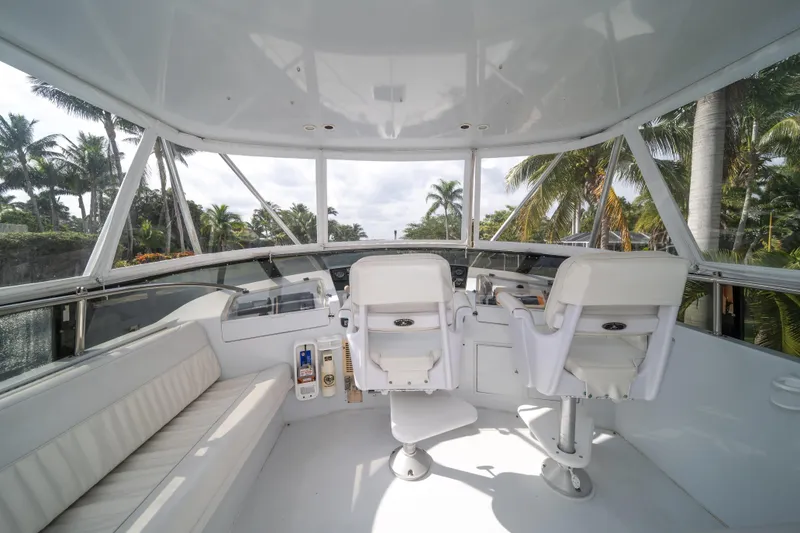 Slide: The Image of 1999 Hatteras 52 Cockpit Motor Yacht helm with white seating and tropical backdrop. - 10