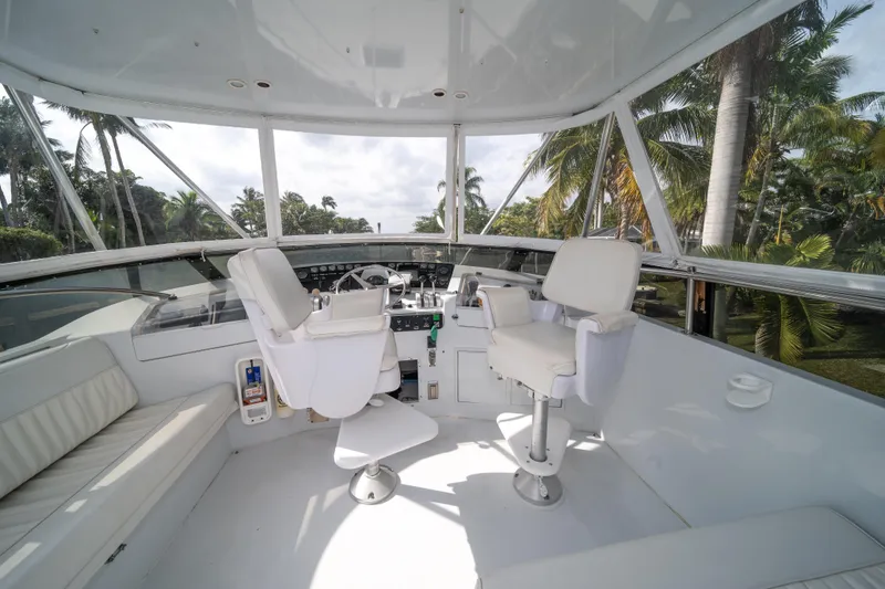 Slide: The Image of 1999 Hatteras 52 Cockpit Motor Yacht helm with white seating and panoramic windows. - 11