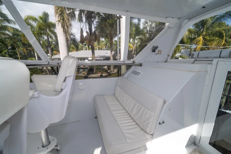Slide: The Image of 1999 Hatteras 52 Cockpit Motor Yacht interior with white seating and tropical view. - 17