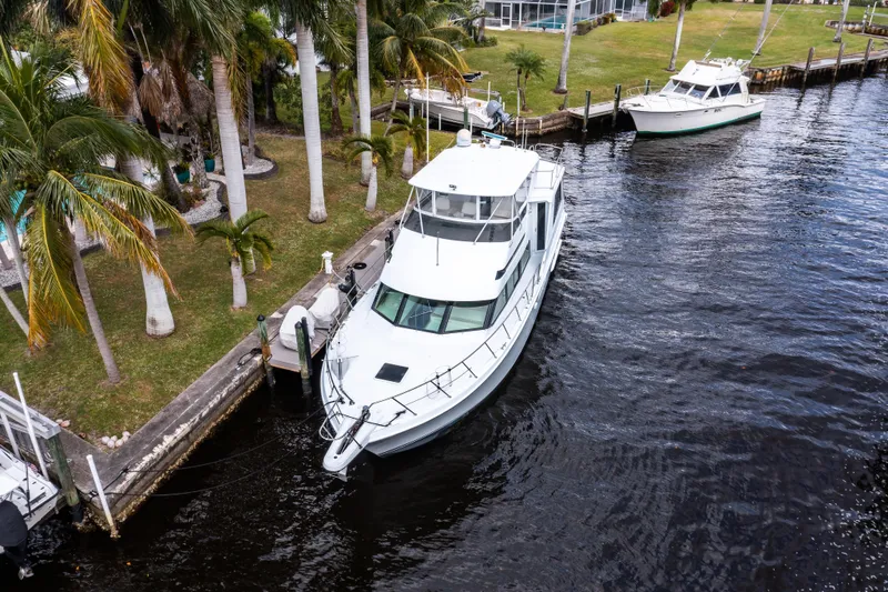 Slide: The Image of 1999 Hatteras 52 Cockpit Motor Yacht docked by palm trees. - 3