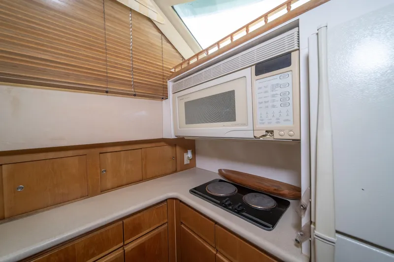 Slide: The Image of 1999 Hatteras 52 Cockpit Motor Yacht kitchen with microwave, stove, and wooden cabinets. - 32
