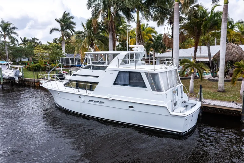 Slide: The Image of 1999 Hatteras 52 Cockpit Motor Yacht docked by palm trees. - 6