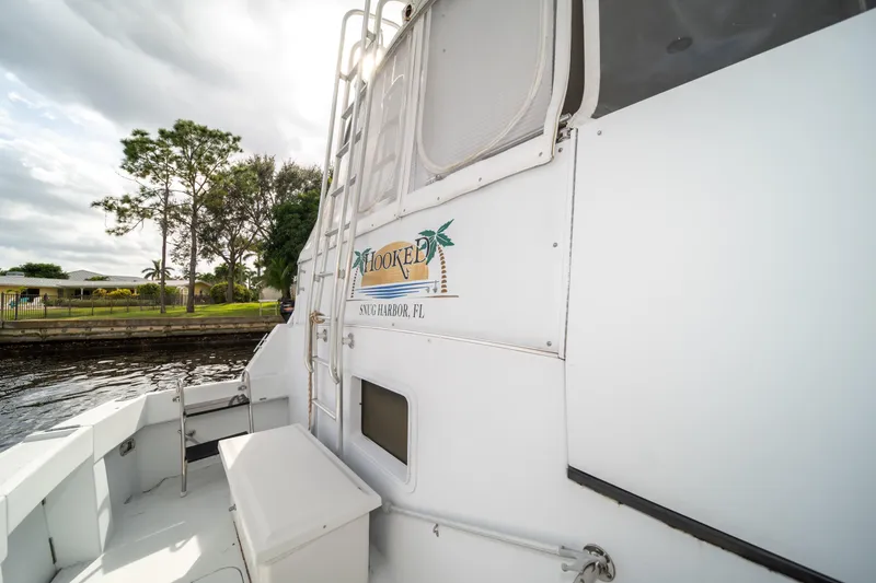 Slide: The Image of 1999 Hatteras 52 Cockpit Motor Yacht docked near lush greenery. - 8
