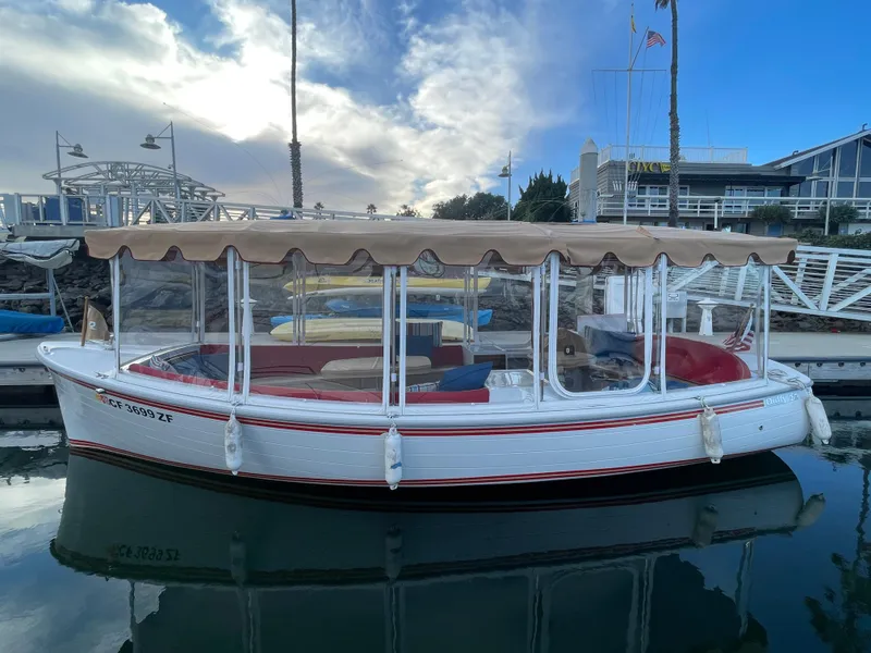 Slide: The Image of 2018 Duffy Bay Island 22 electric boat docked in marina, featuring canopy and clear side panels. - 2