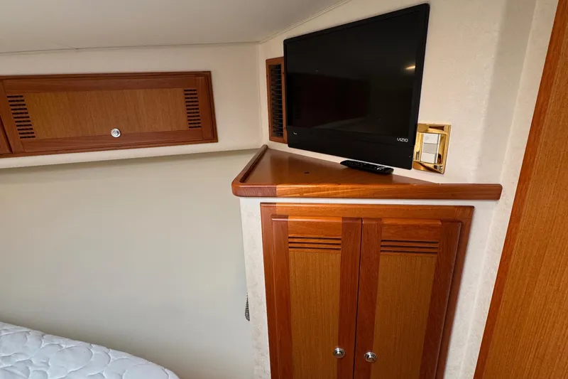 Slide: The Image of 2005 Cabo 40 Express cabin with TV, wooden cabinets, and bed corner. - 17