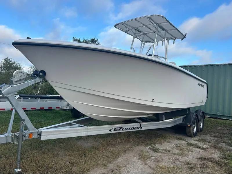 Slide: The Image of 2024 Aquasport 2200 CC boat on trailer, parked outdoors under blue sky. - 13