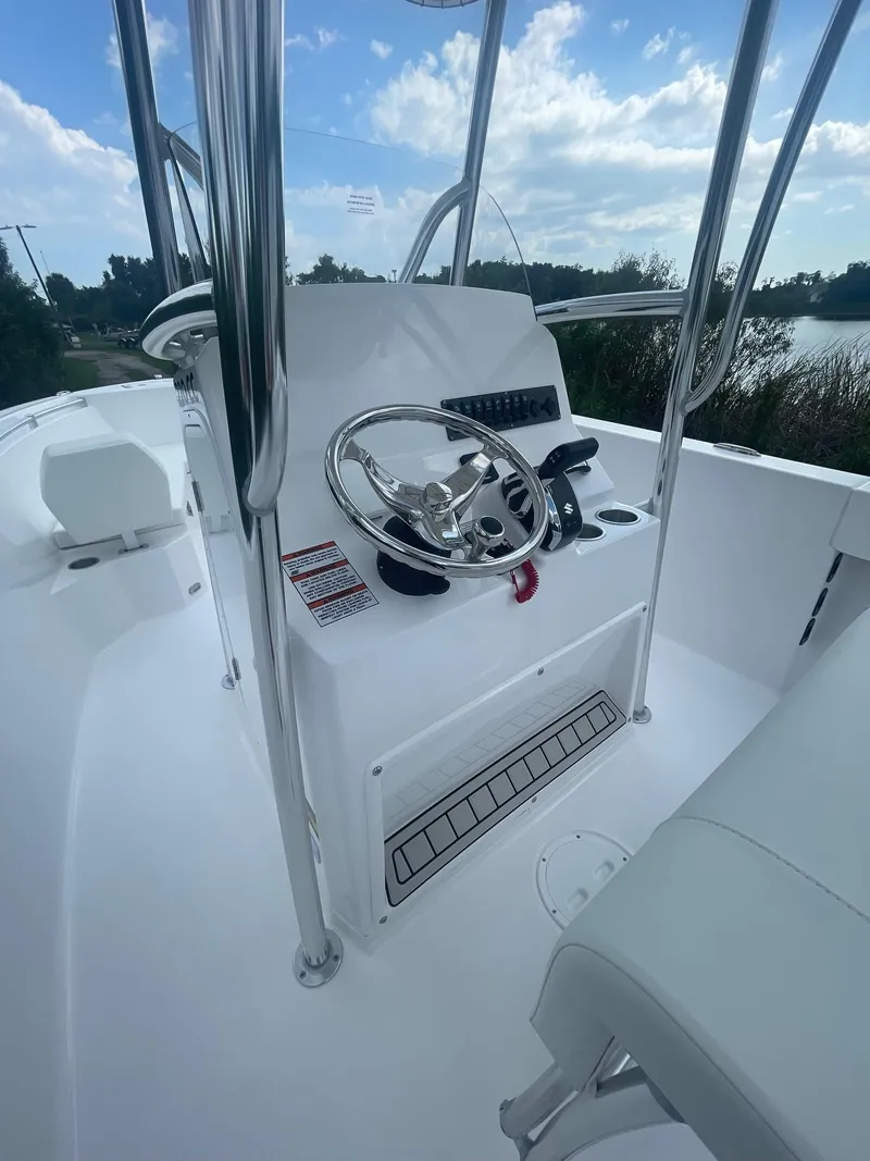 Slide: The Image of 2024 Aquasport 220 CC boat console with steering wheel and controls, under a blue sky. - 16