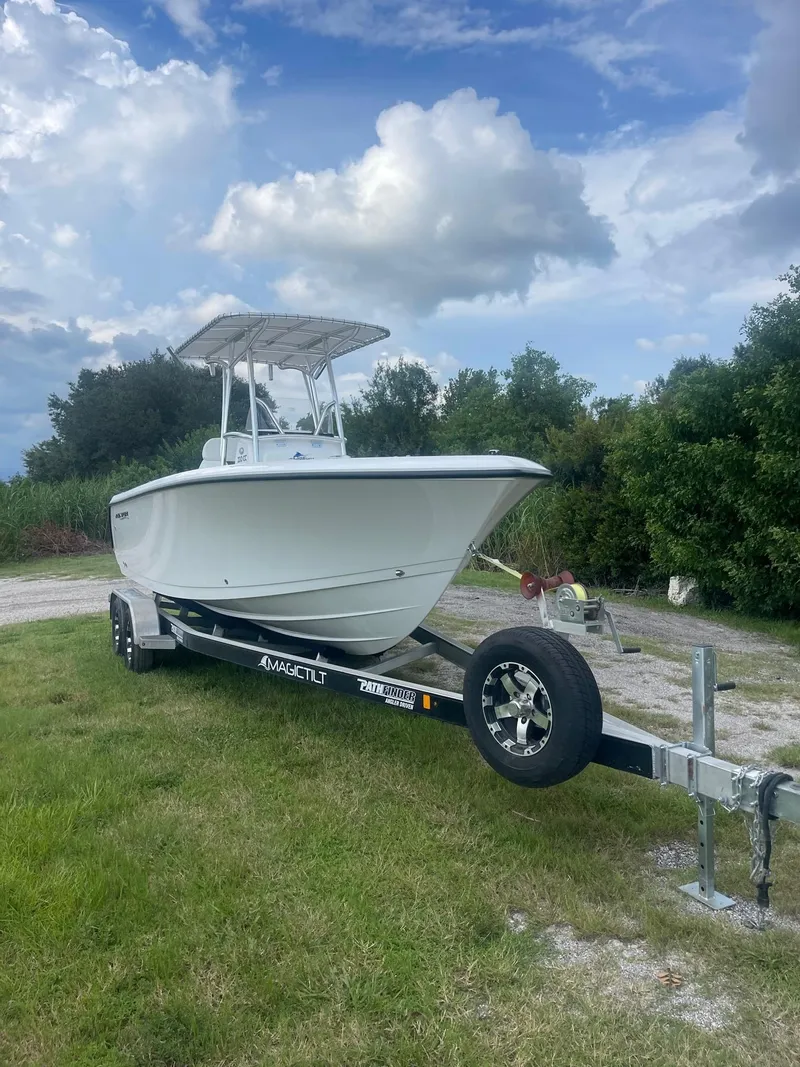Slide: The Image of 2024 Aquasport 220 CC boat on trailer, parked on grassy area under cloudy sky. - 18