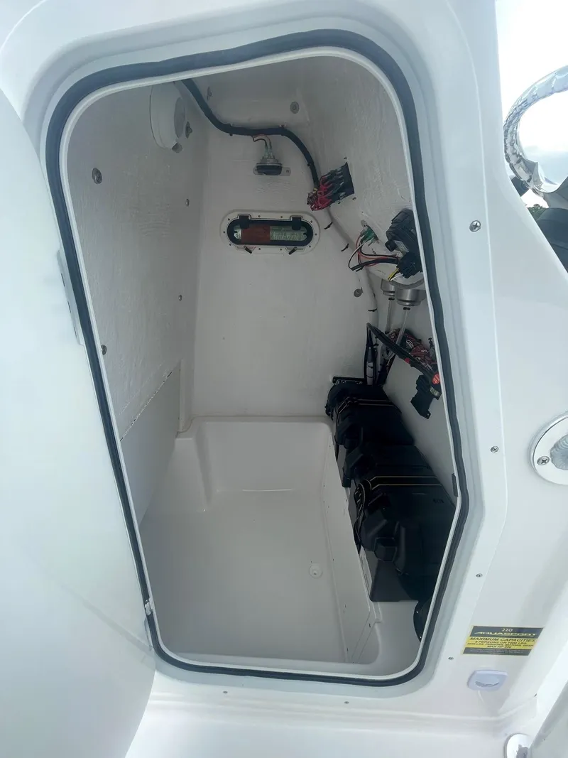 Slide: The Image of 2024 Aquasport 220 CC storage compartment with wiring and battery setup. - 4