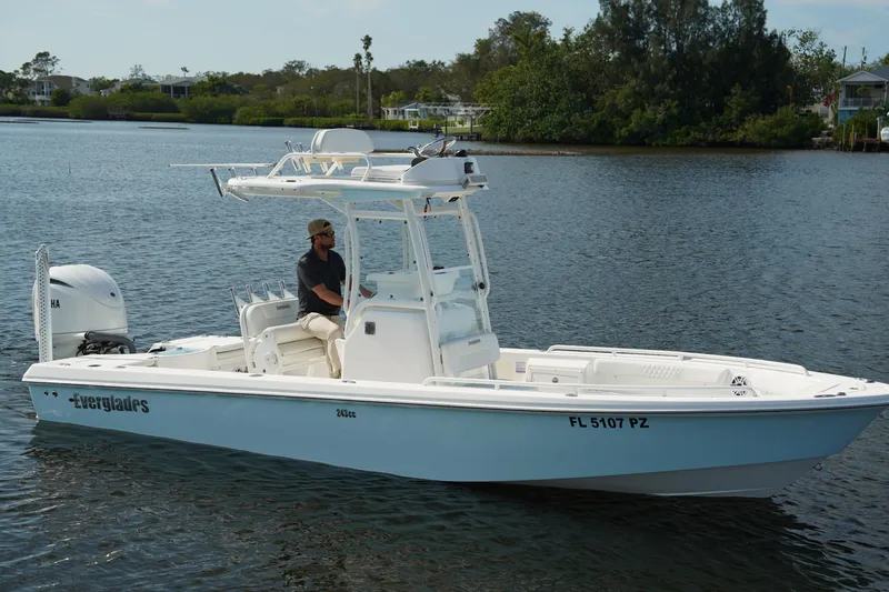 Slide: The Image of 2015 Everglades 243 CC boat on calm water with a person at the helm. - 0