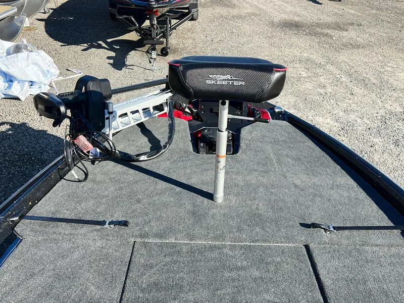 Slide: The Image of 2025 Skeeter ZXR 21 boat deck with motor and seat, parked on gravel. - 11