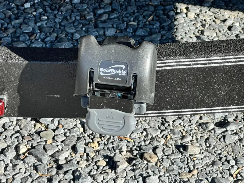 Slide: The Image of BoatBuckle on Skeeter ZXR 21 trailer, 2025 model, on gravel surface. - 15