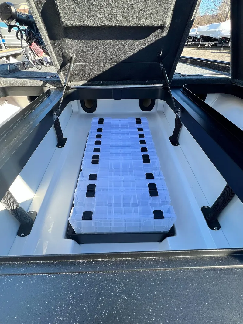 Slide: The Image of Open storage compartment of 2025 Skeeter ZXR 21 boat with organized tackle boxes. - 24