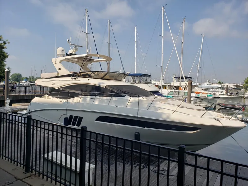 The Image of 2016 Sea Ray L590 Fly yacht docked at marina with sailboats in background. - 0