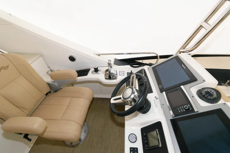 Slide: The Image of 2016 Sea Ray L590 Flybridge helm with beige captain's chair and modern controls. - 10