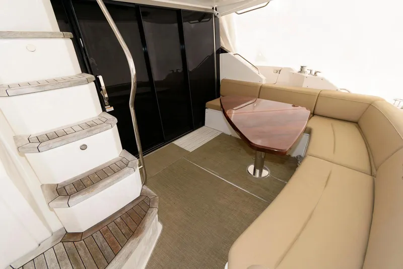 Slide: The Image of 2016 Sea Ray L590 Fly yacht interior with curved seating and wooden table. - 5