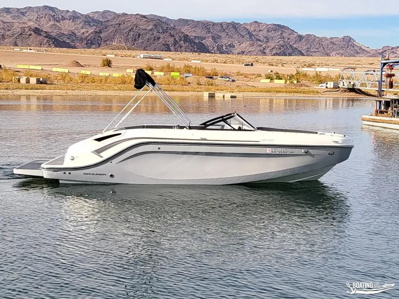 Slide: The Image of 2021 Bayliner DX 2250 boat on a calm lake with mountainous backdrop. - 0