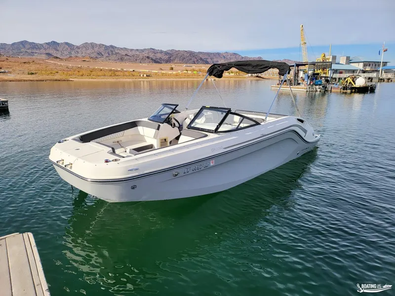 Slide: The Image of 2021 Bayliner DX 2250 boat on calm water with scenic mountain backdrop. - 1