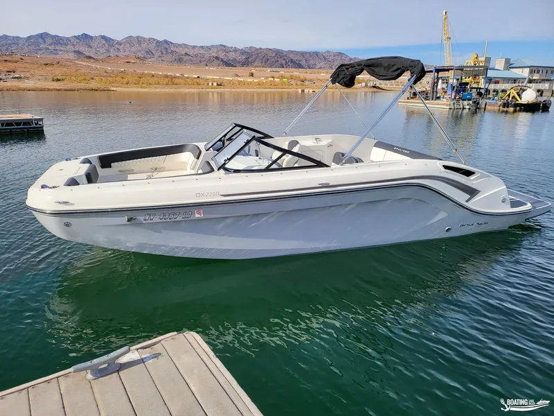 Slide: The Image of 2021 Bayliner DX 2250 boat docked on a serene lake. - 2