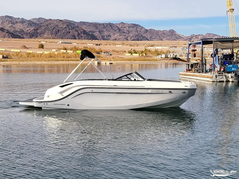Slide: The Image of 2021 Bayliner DX 2250 boat on a calm lake with mountains in the background. - 3