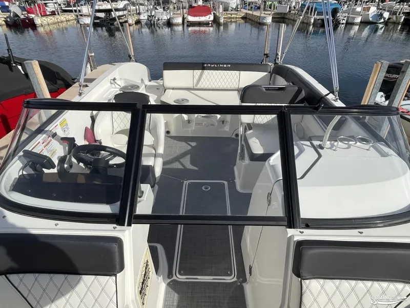 Slide: The Image of 2021 Bayliner DX 2250 boat interior at marina, featuring steering wheel and seating. - 4