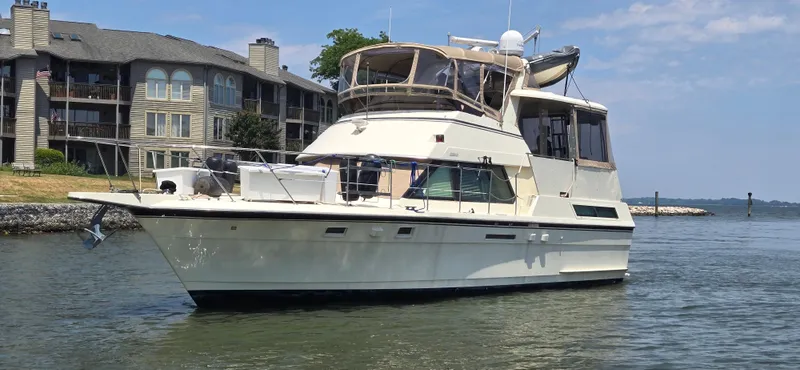 Slide: The Image of 1989 Hatteras 40 Double Cabin yacht on calm water near waterfront homes. - 2
