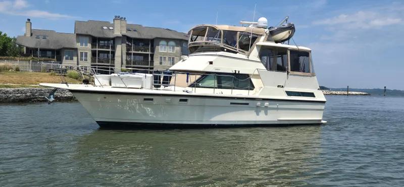 Slide: The Image of 1989 Hatteras 40 Double Cabin yacht on calm water near luxury homes. - 3