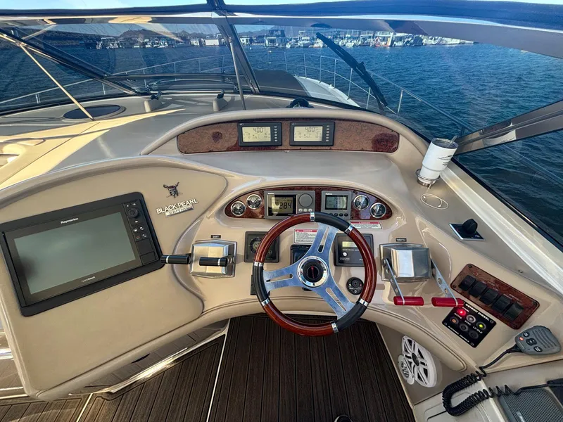 Slide: The Image of 1999 Sea Ray 540 Sundancer helm with navigation controls and steering wheel on open water. - 14