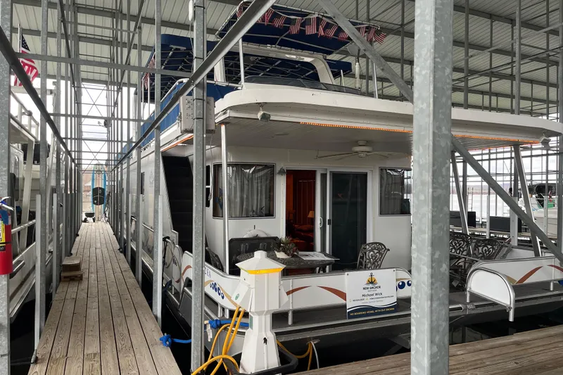 The Image of Houseboat docked in marina, Funtime 68x16 model, 2010, with outdoor seating area. - 1