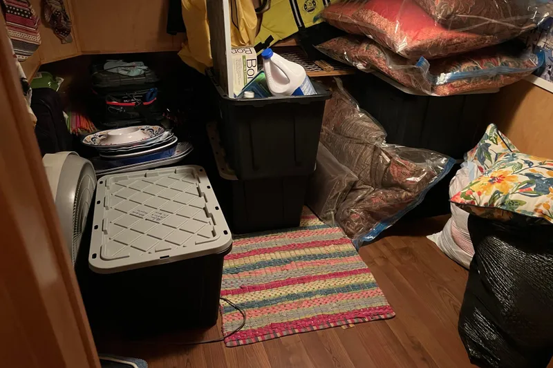 Slide: The Image of Storage room with plastic bins, stacked pillows, and colorful rug on wooden floor. - 19