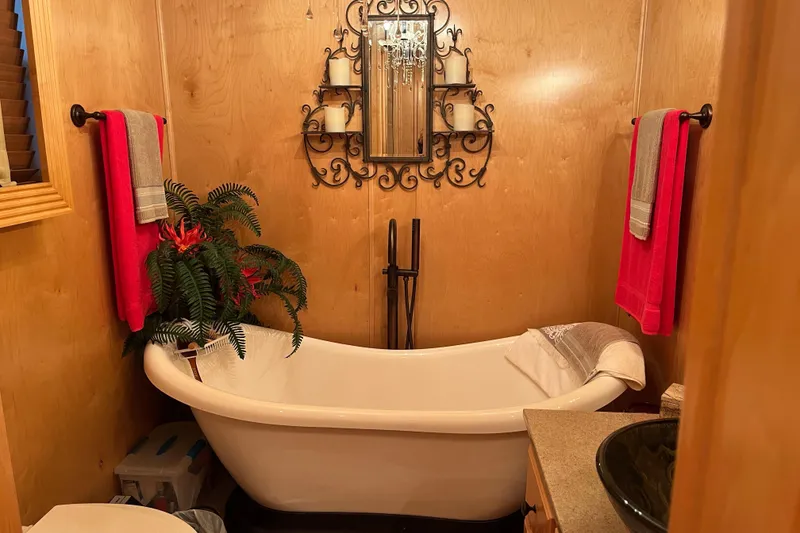 Slide: The Image of Cozy bathroom with clawfoot tub, decorative mirror, and red towels in a Funtime 68x16 model. - 26