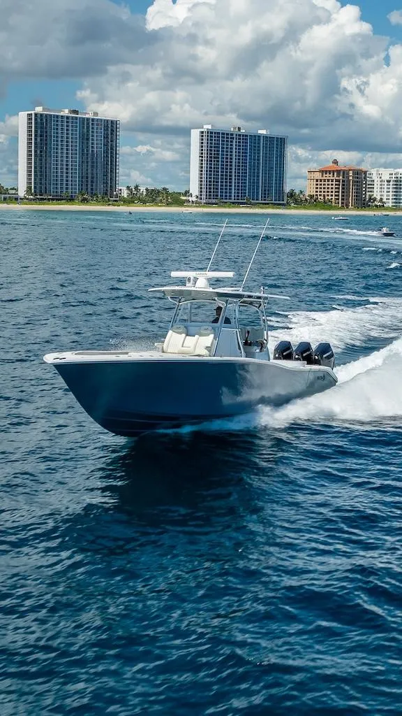 Slide: The Image of 2025 Billfish 39 Center Console boat cruising near coastal skyscrapers. - 32