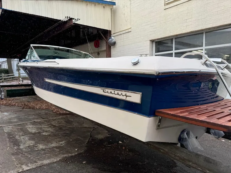 Slide: The Image of 1998 Century Coronado boat with blue and white exterior, docked near a building. - 12