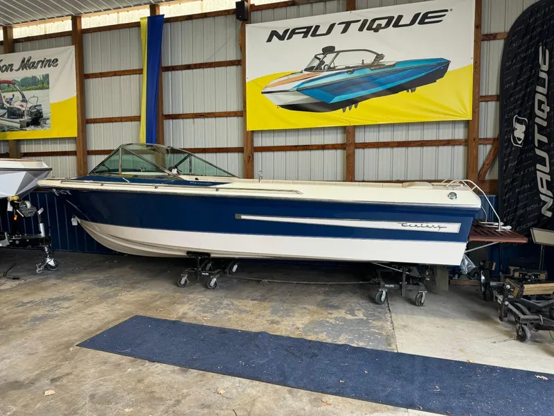 Slide: The Image of 1998 Century Coronado boat in storage, blue and white, under Nautique banner. - 15