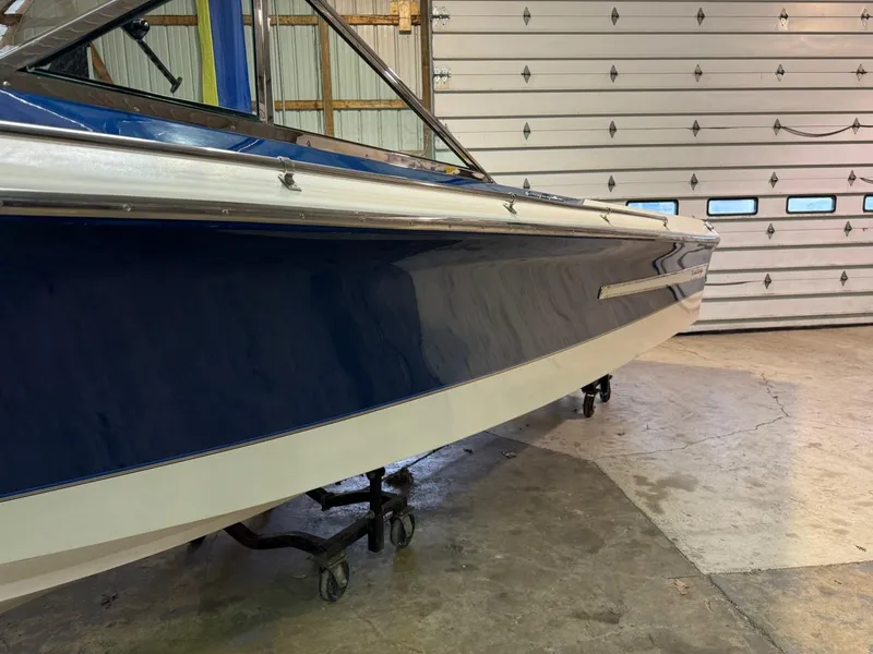 Slide: The Image of 1998 Century Coronado boat in garage, blue and white hull, on wheeled stand. - 21