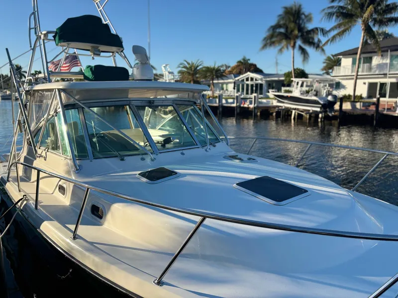 Slide: The Image of 2000 Pursuit 3400 Express boat with tower docked by waterfront homes. - 2