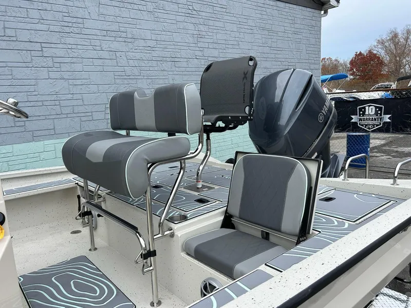 Slide: The Image of 2025 Xpress X23 Bay Lounge boat with gray seating and powerful outboard motor. - 8
