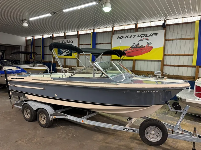 Slide: The Image of 1985 Coronado Cardel boat on trailer in showroom, featuring blue and white design. - 14