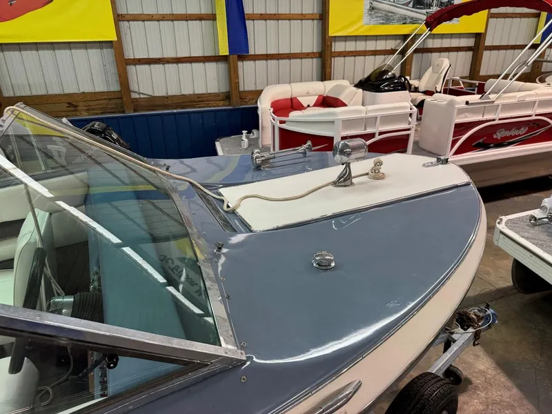 Slide: The Image of 1985 Coronado Cardel boat in showroom, blue and white exterior, alongside other boats. - 15