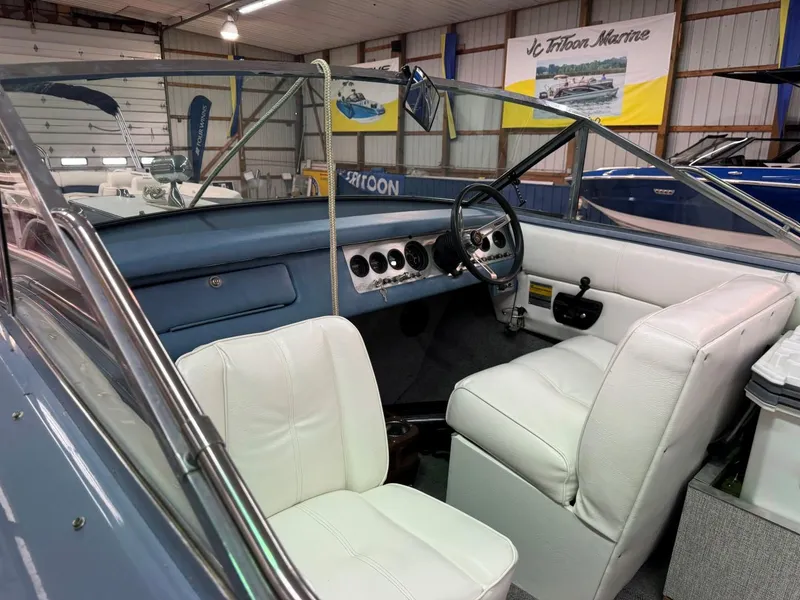 Slide: The Image of 1985 Coronado Cardel boat interior with white seats and classic dashboard in showroom. - 21
