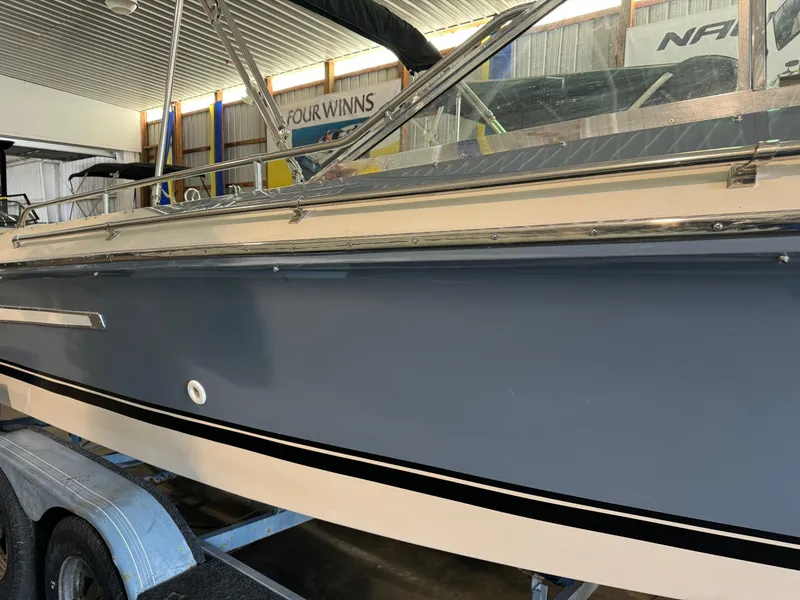 Slide: The Image of 1985 Coronado Cardel boat in storage, blue and white exterior, on a trailer. - 30