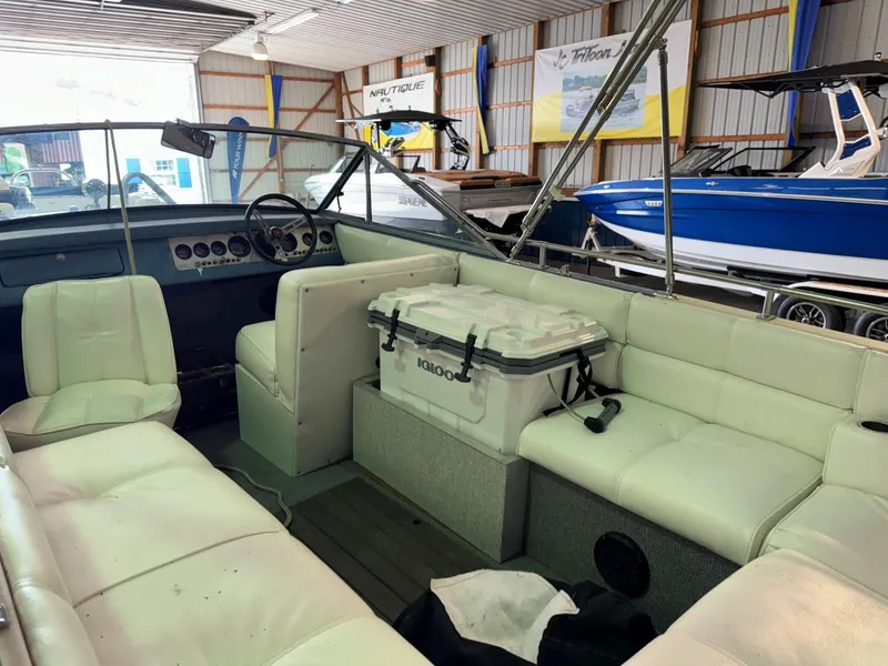 Slide: The Image of 1985 Coronado Cardel boat interior with white seating and cooler in a storage facility. - 7