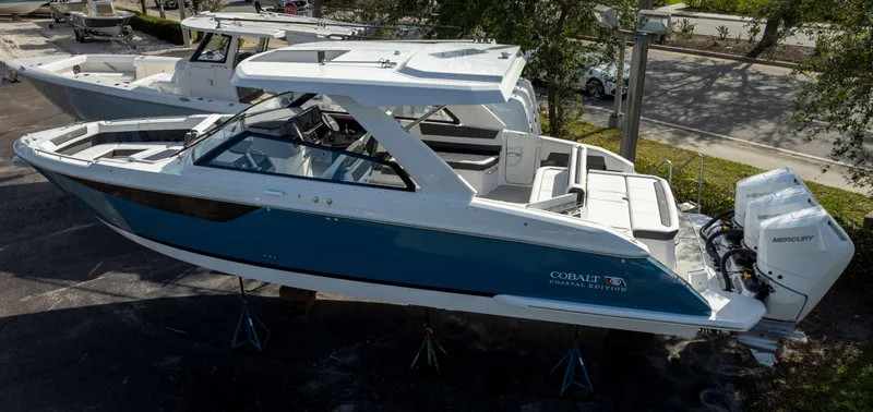 Slide: The Image of 2025 Cobalt R35 boat with dual Mercury engines, blue and white design, docked outdoors. - 1