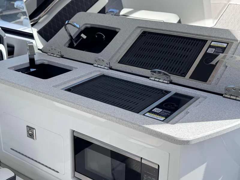 Slide: The Image of Cobalt R35 2025 boat kitchen with grill, sink, and microwave. - 31