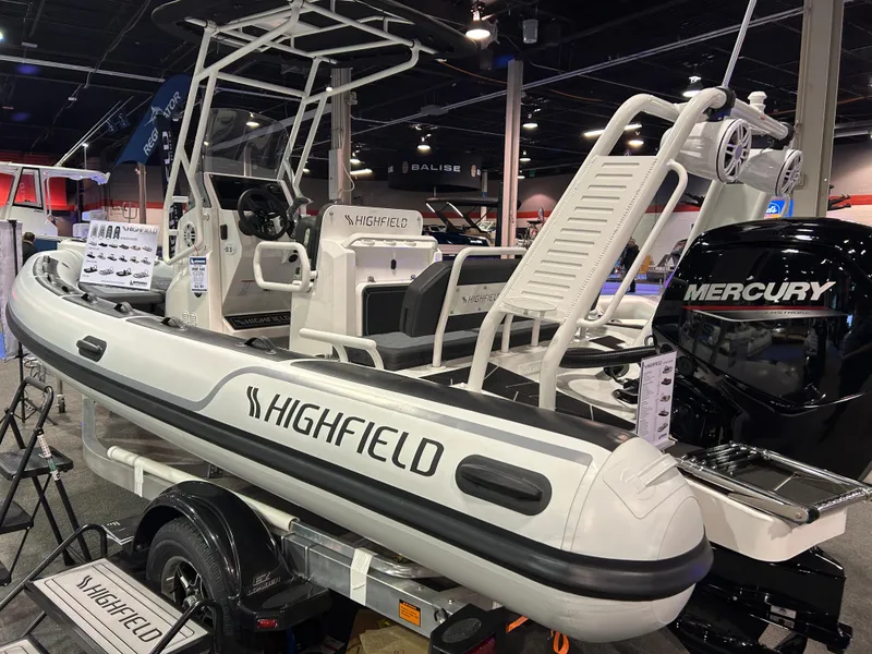 Slide: The Image of 2025 Highfield Sport 560 boat displayed indoors with Mercury engine. - 2